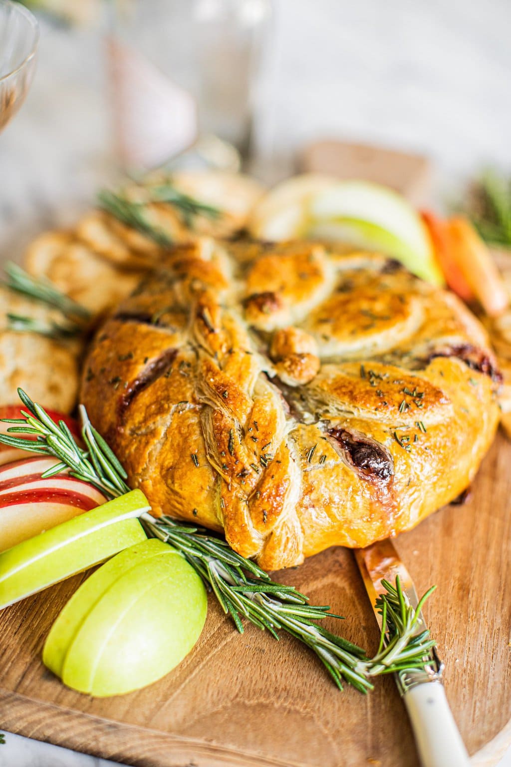 Baked brie on a wooden board with a serving knife. 