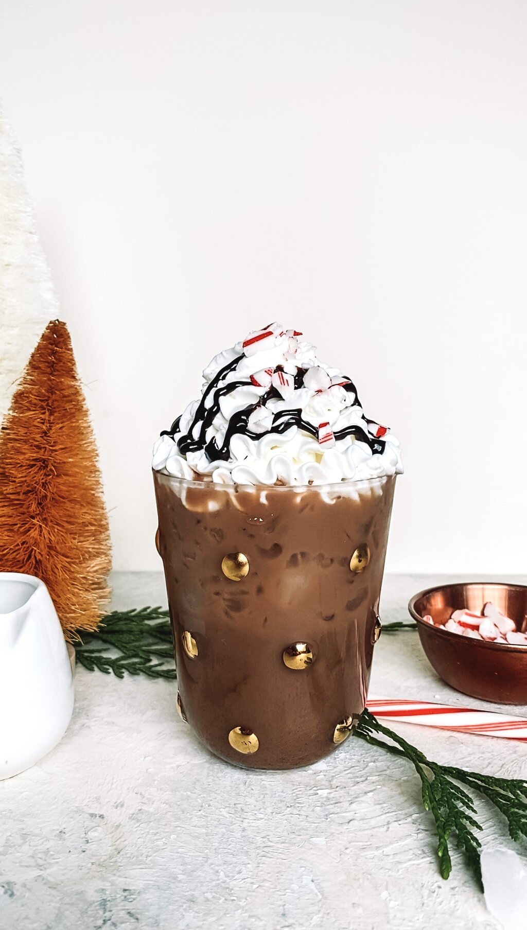 Iced peppermint mocha in a small glass with cold embellishments.