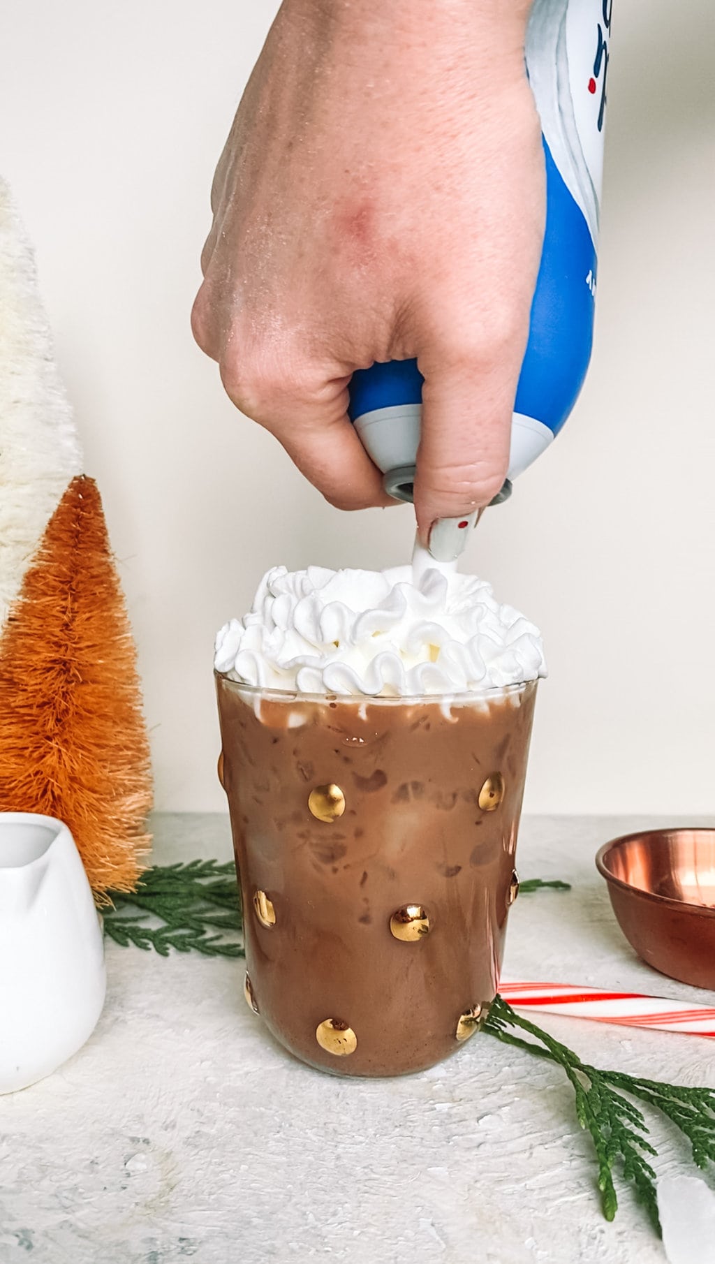 Canned whip cream being topped on an iced peppermint mocha.