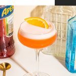 gin aperol cocktail in coupe glass garnished with orange