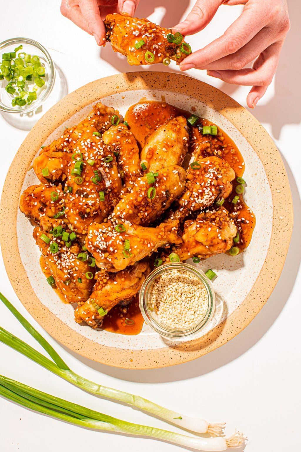 Chicken wings on a tan plate with one wing being grabbed