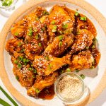 chicken wings on a cream plate with one wing being grabbed