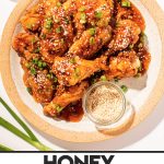 honey garlic soy chicken wings on a cream plate with a side of sesame seeds