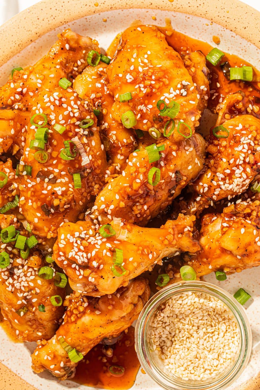 honey soy garlic chicken wings on a tan plate with a side of sesame seeds