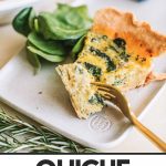 slice of spinach quiche on a plate with fresh spinach and fork