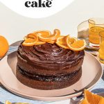 Chocolate orange cake on a pink platter with orange slices