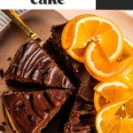 Chocolate orange cake on a pink platter with orange slices