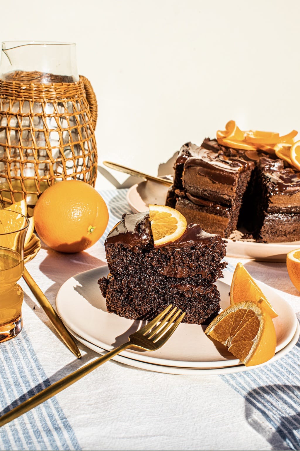 a slice of chocolate orange cake on a pink plate with a gold fork 