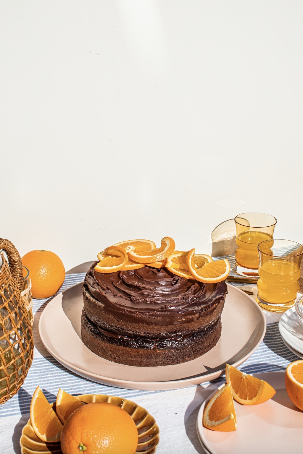 chocolate cake on top of a pink platter with oranges slices and chocolate ganache on top 