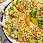 Italian chopped salad in large bowl with serving utensils