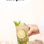 hand holding highball glass filled with virgin mint mocktail with lime wheels and fresh mint