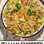 hand tossing chopped salad in large bowl with fork