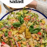 hand tossing chopped salad in large bowl with fork