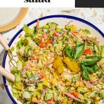 Italian chopped salad in large bowl with serving utensils