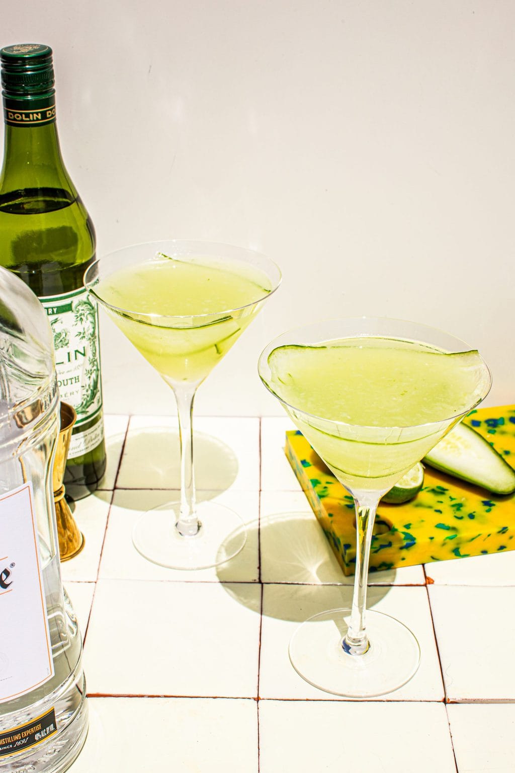 two cucumber martinis in martini glasses with dry vermouth on the side