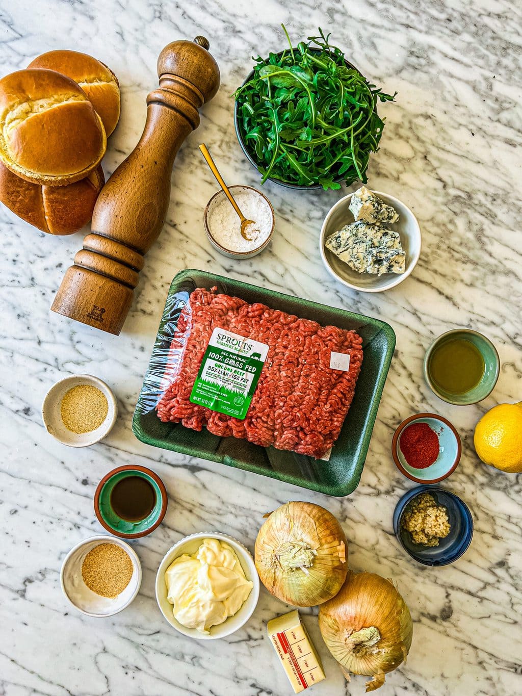 brioche buns, pepper mill, salt, arugula, blue cheese, ground beef, ground spices, onions