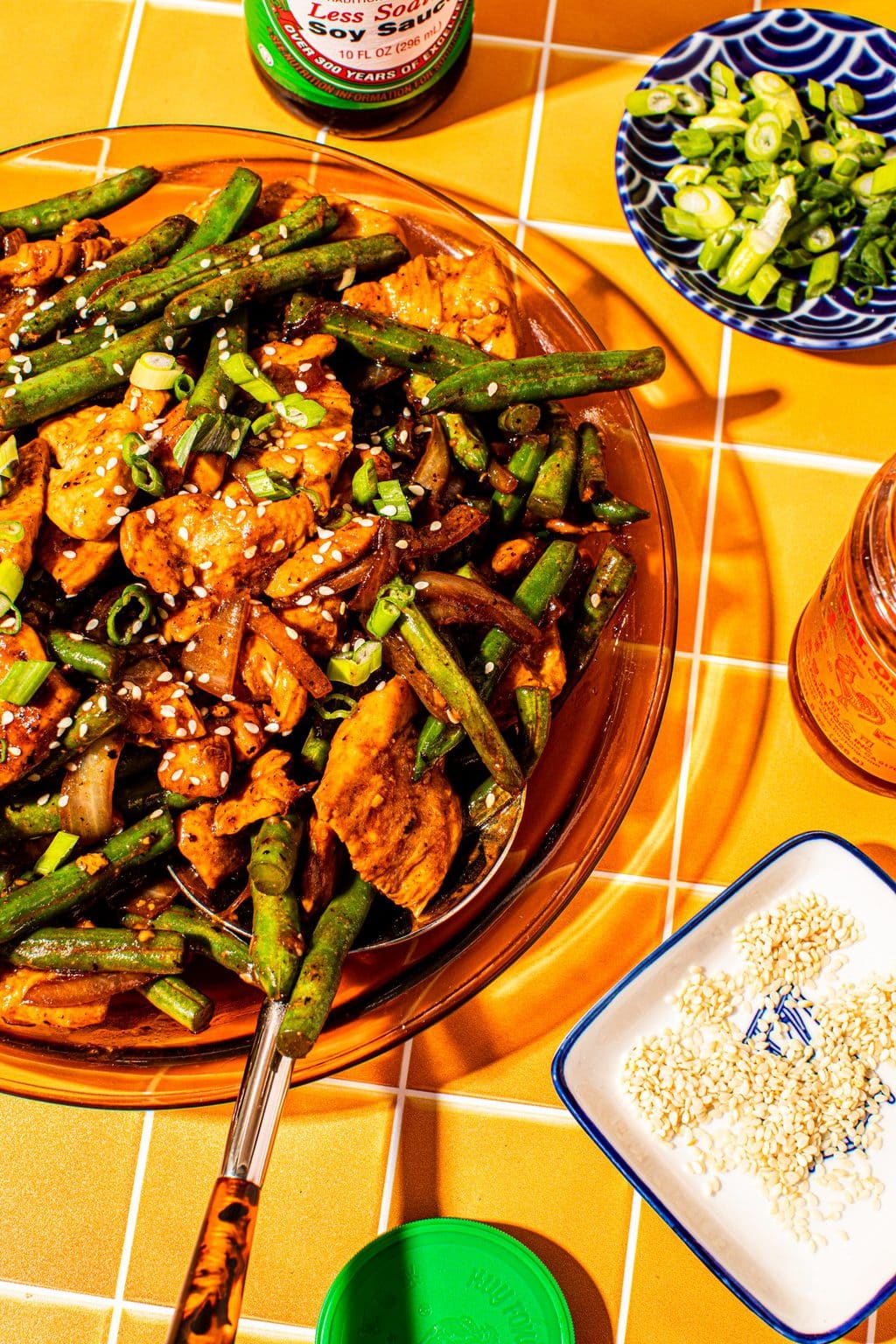 string bean chicken on large glass platter with sesame seeds on side