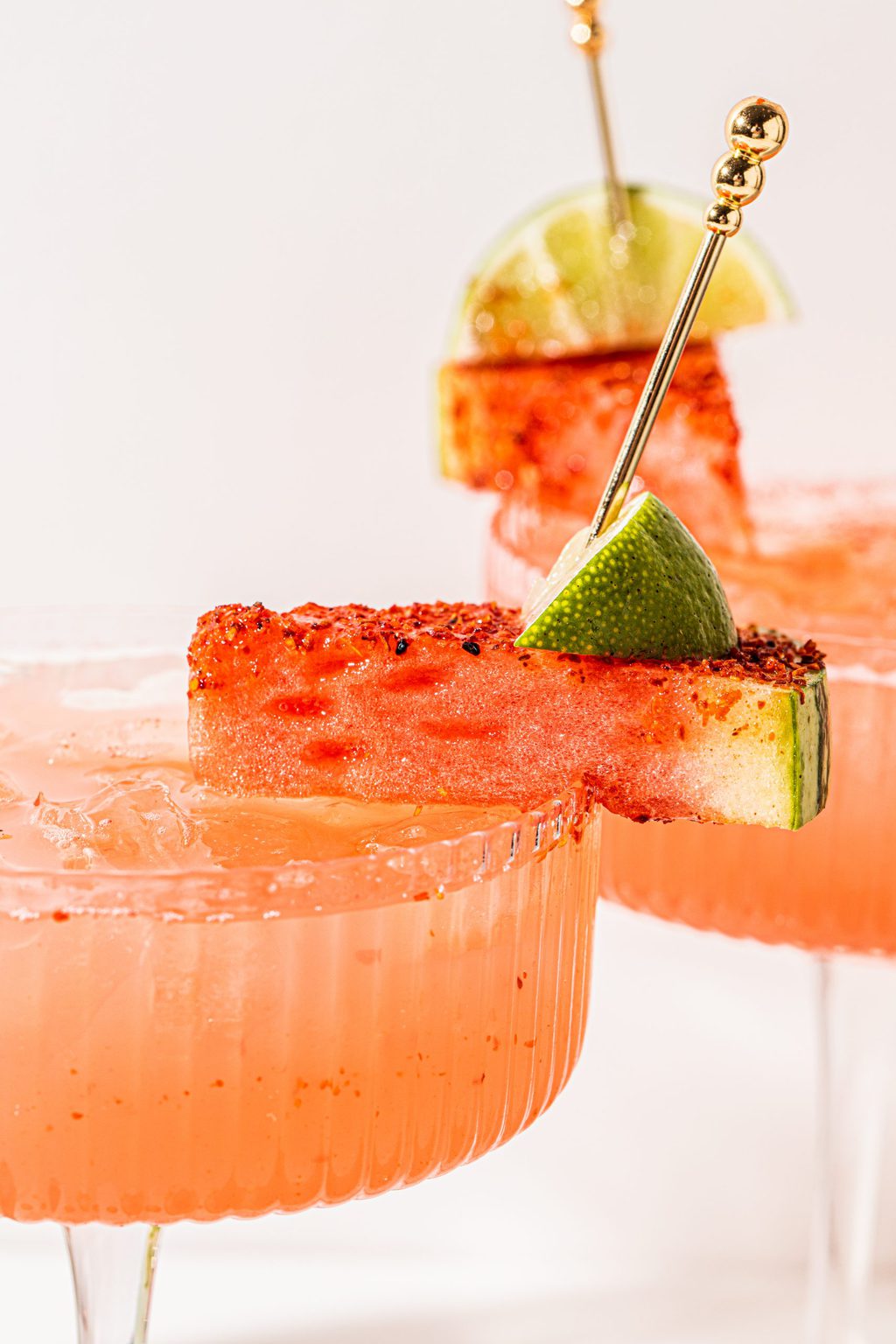 coupe glass filled with spritzer and garnished with a watermelon and lime