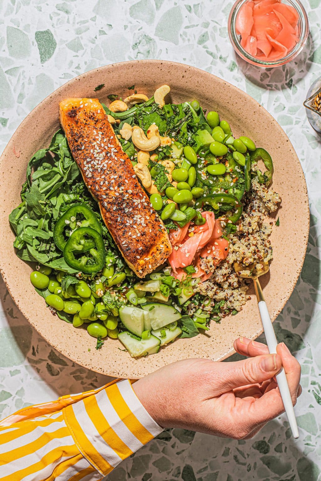 hand digging fork into salmon edamame bowl