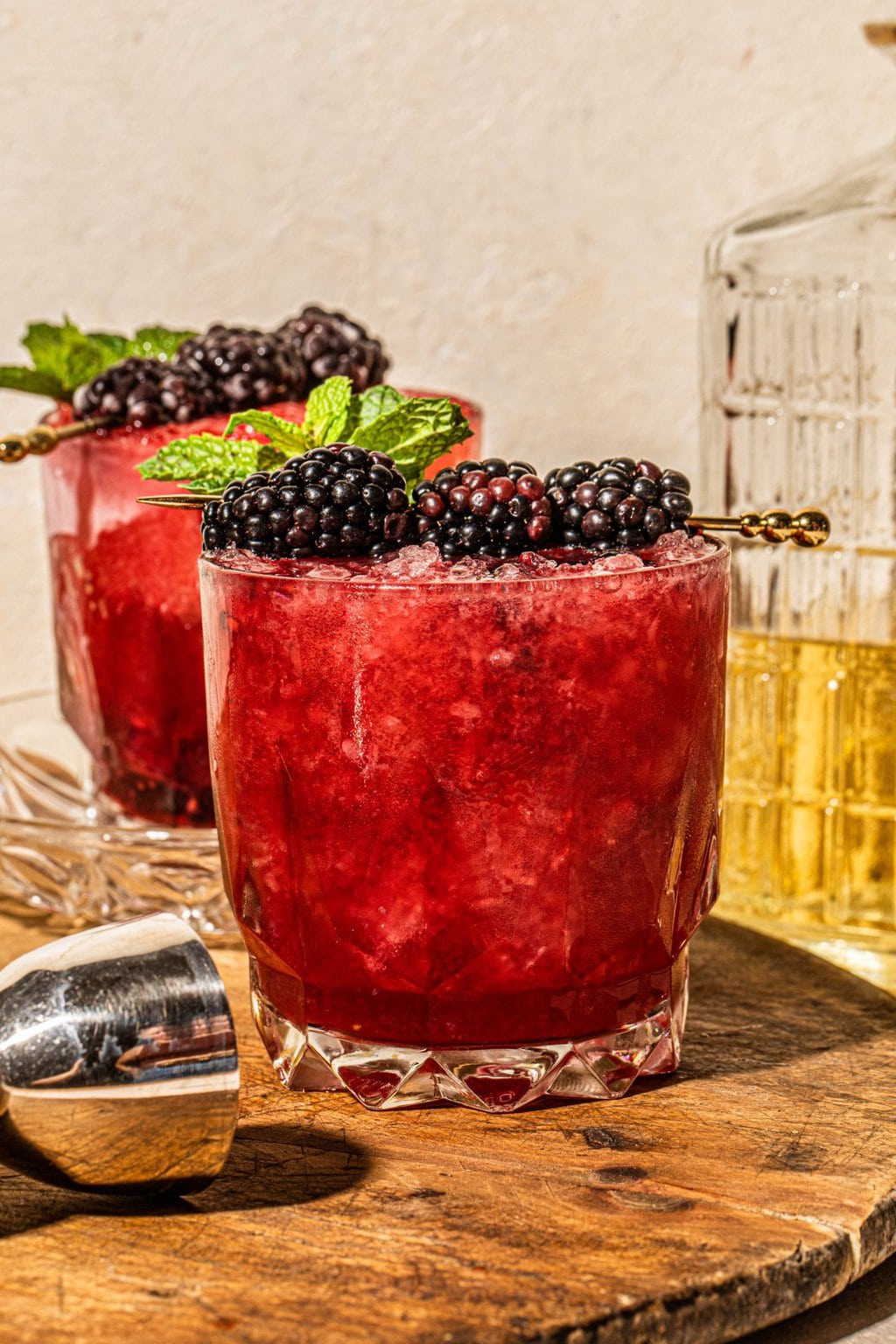 a glass filled with blackberry bourbon smash topped with a gold cocktail pick with blackberries 