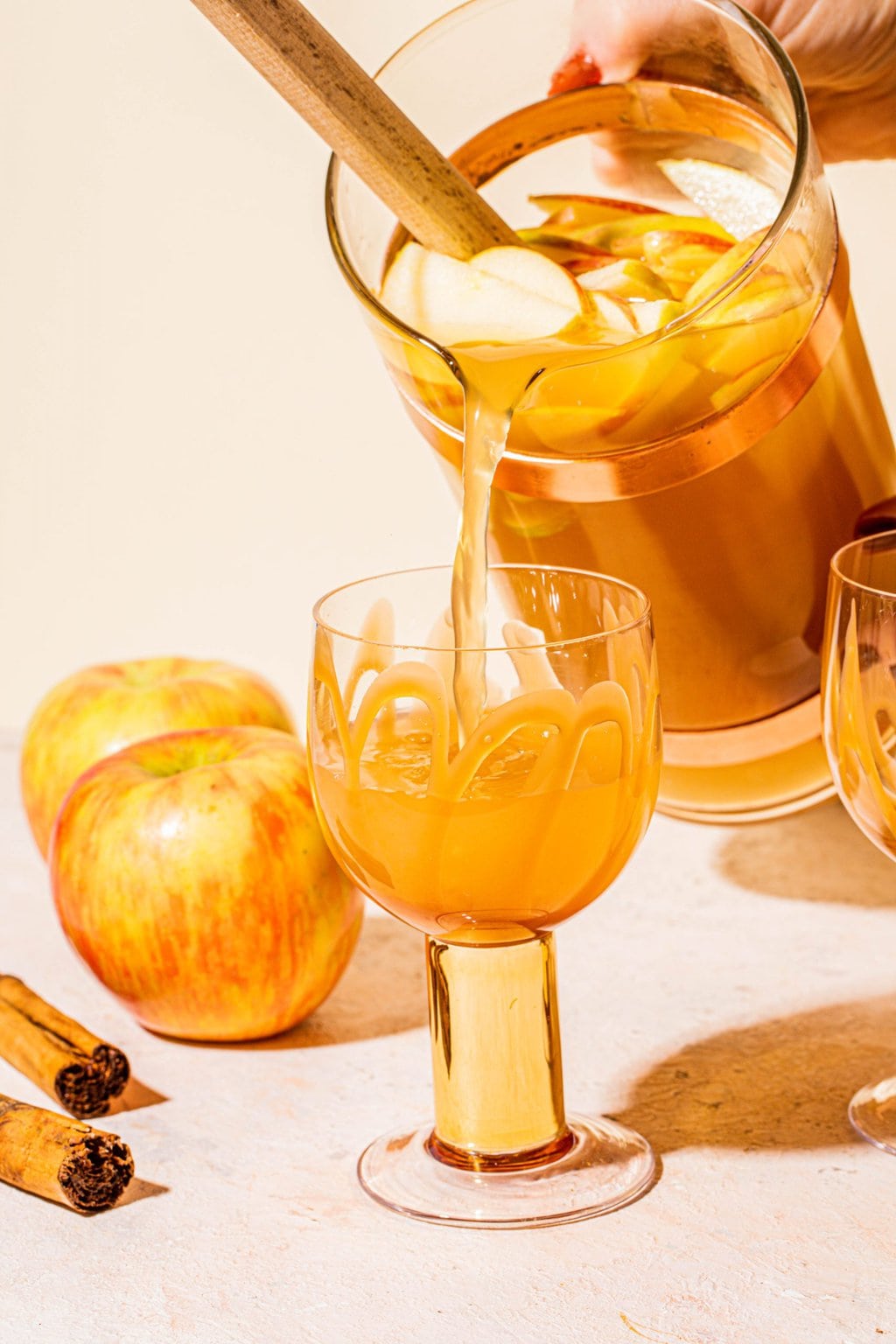 pouring caramel apple cider sangria into glass from pitcher