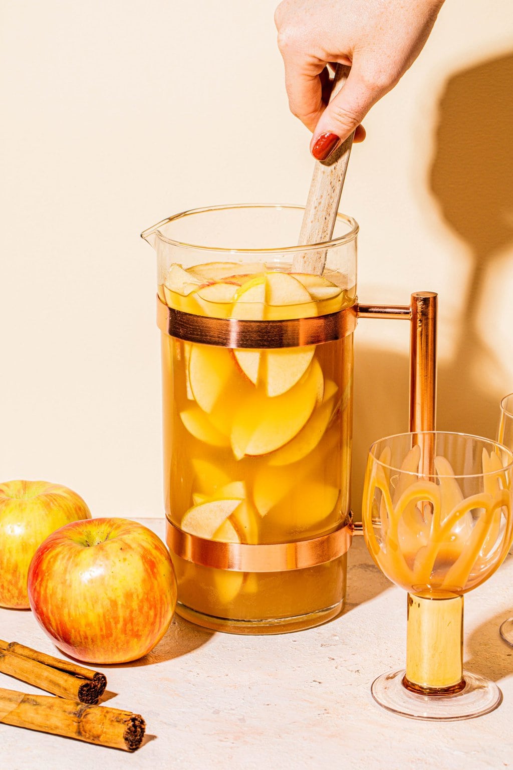 hand stirring caramel apple sangria in pitcher