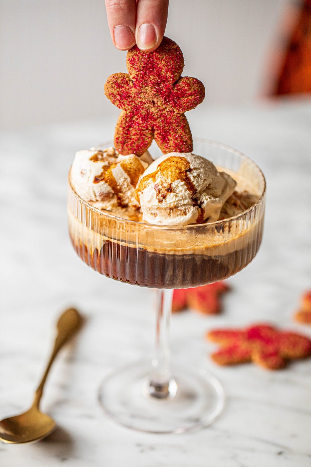 hand placing gingerbread man cookie on top of affogato