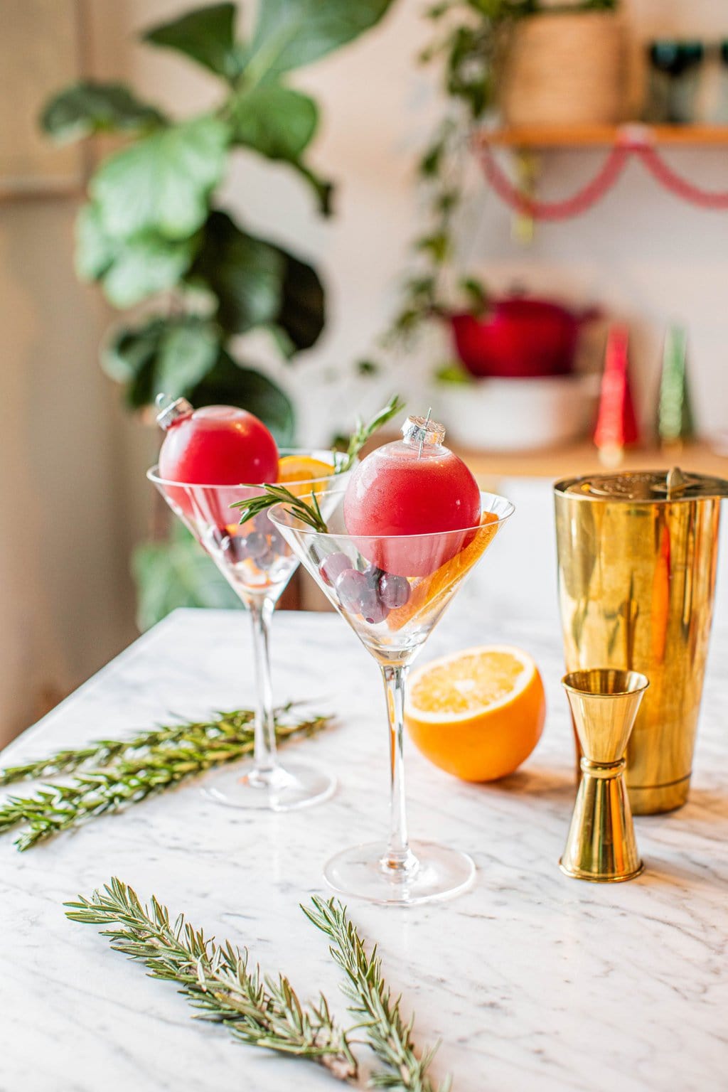 two glass ornaments filled with christmas cocktail placed in martini glasses