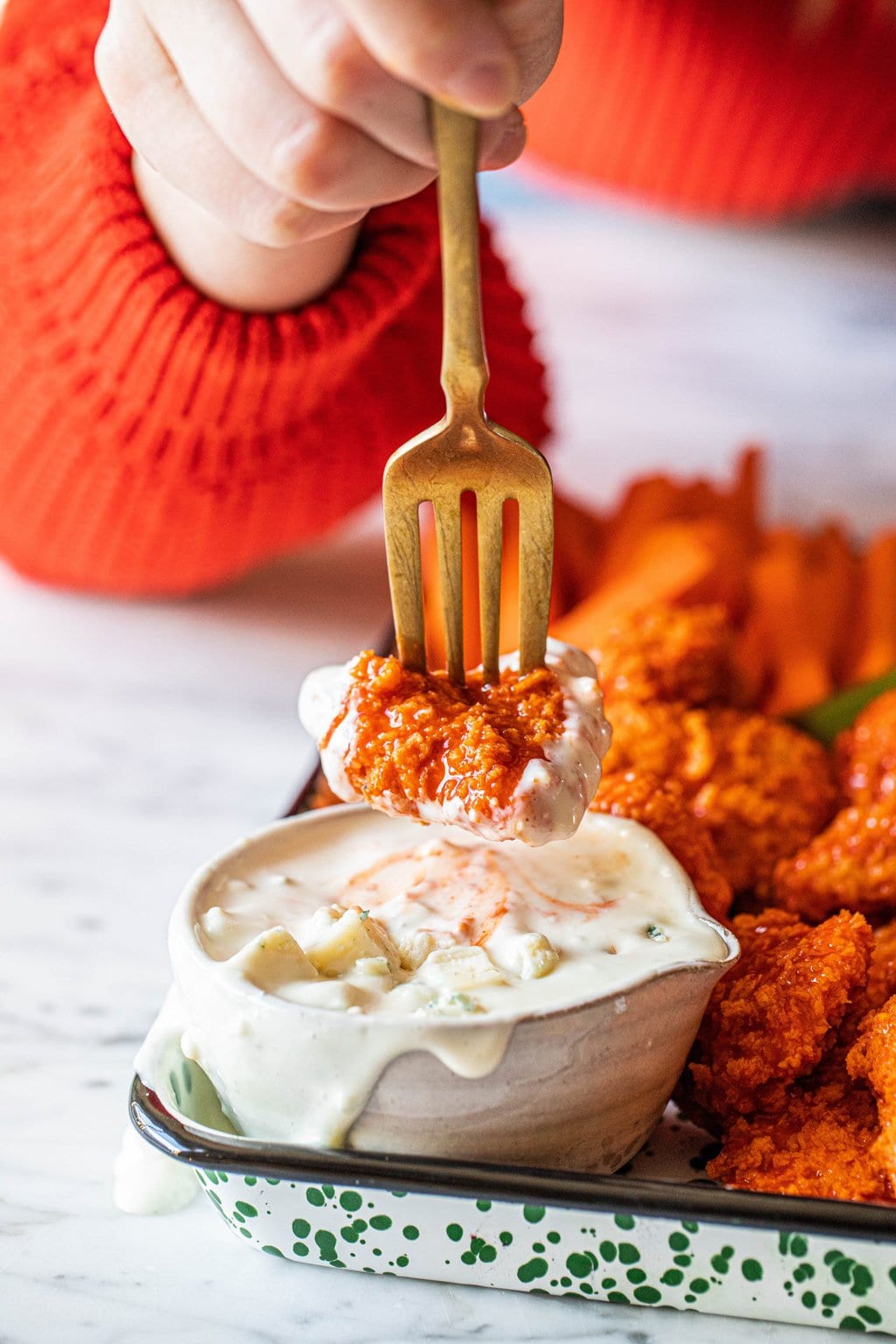 buffalo chicken bite on fork dipping into blue cheese sauce