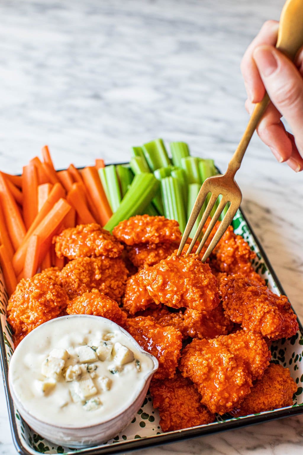 buffalo chicken bites on platter with celery, carrots, blue cheese dressing