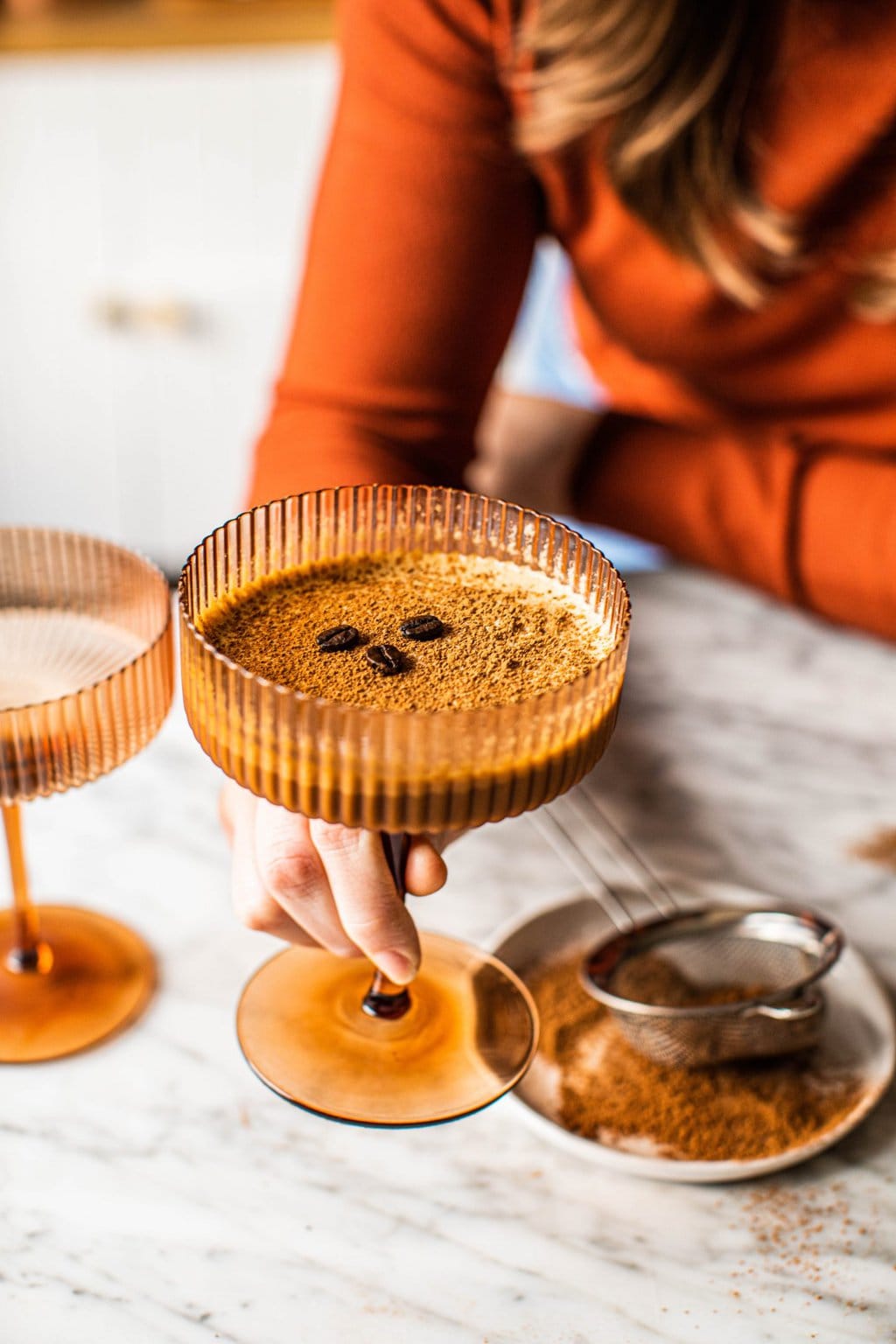 A brown coupe glass filled with espresso martini ingredients topped with espresso beans. 