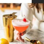 hand holding pink lady mocktail in coupe glass