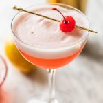 pink lady mocktail recipe in coupe glass garnished with maraschino cherry