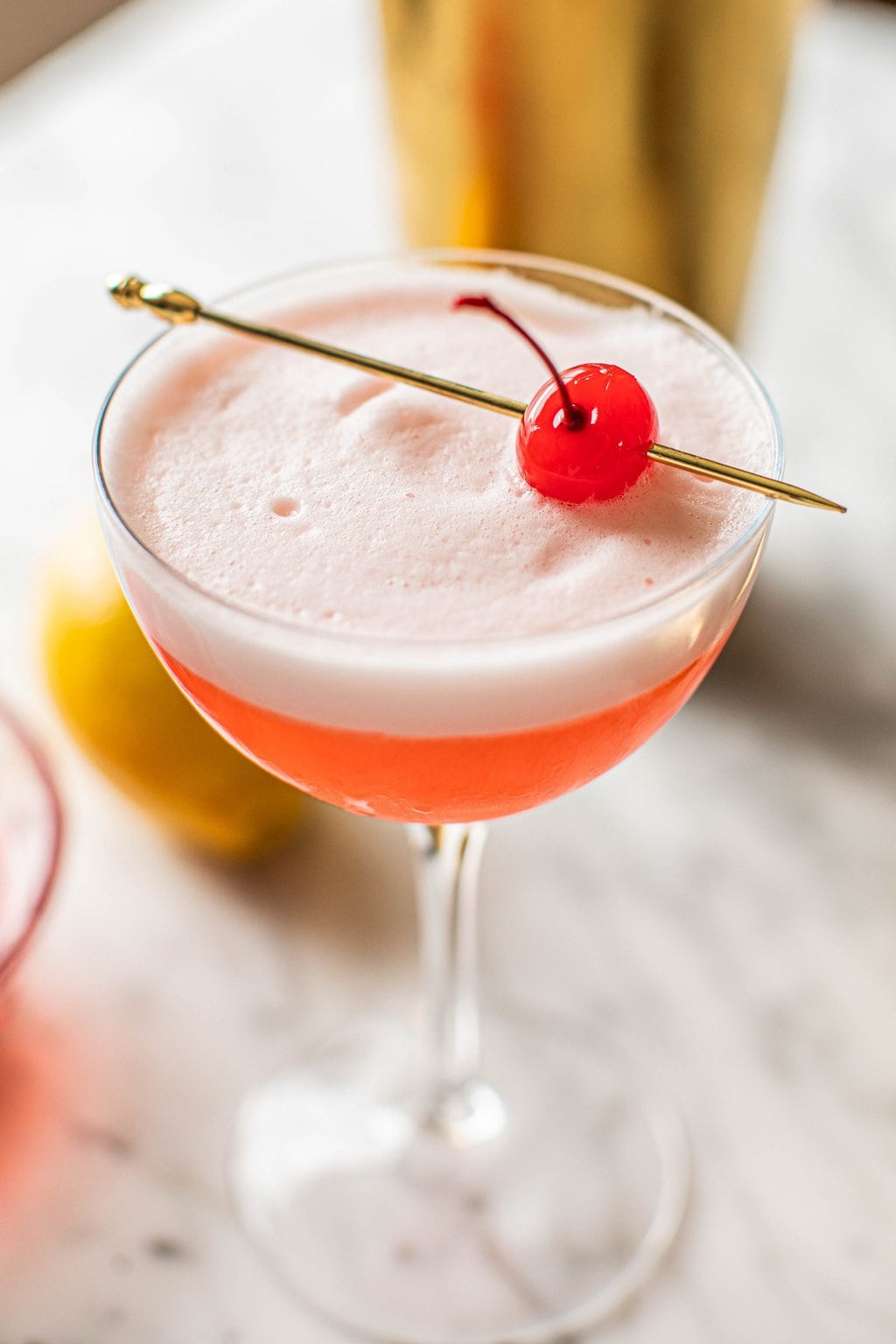 pink lady mocktail recipe in coupe glass garnished with maraschino cherry