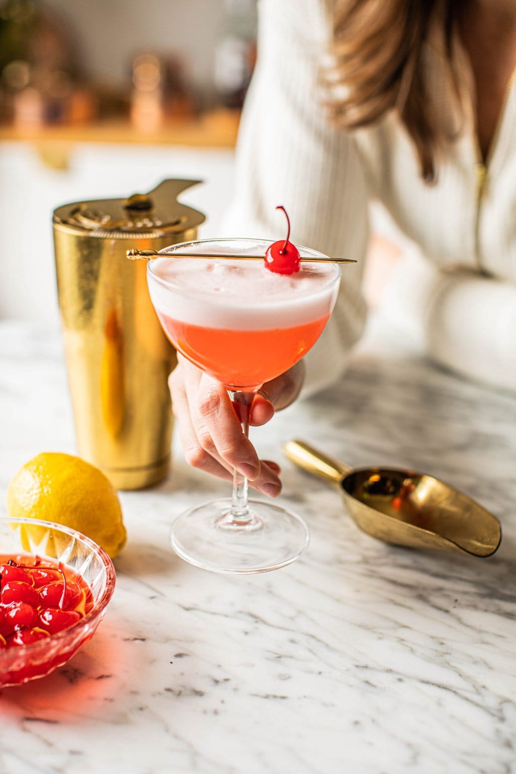 hand holding pink lady mocktail in coupe glass