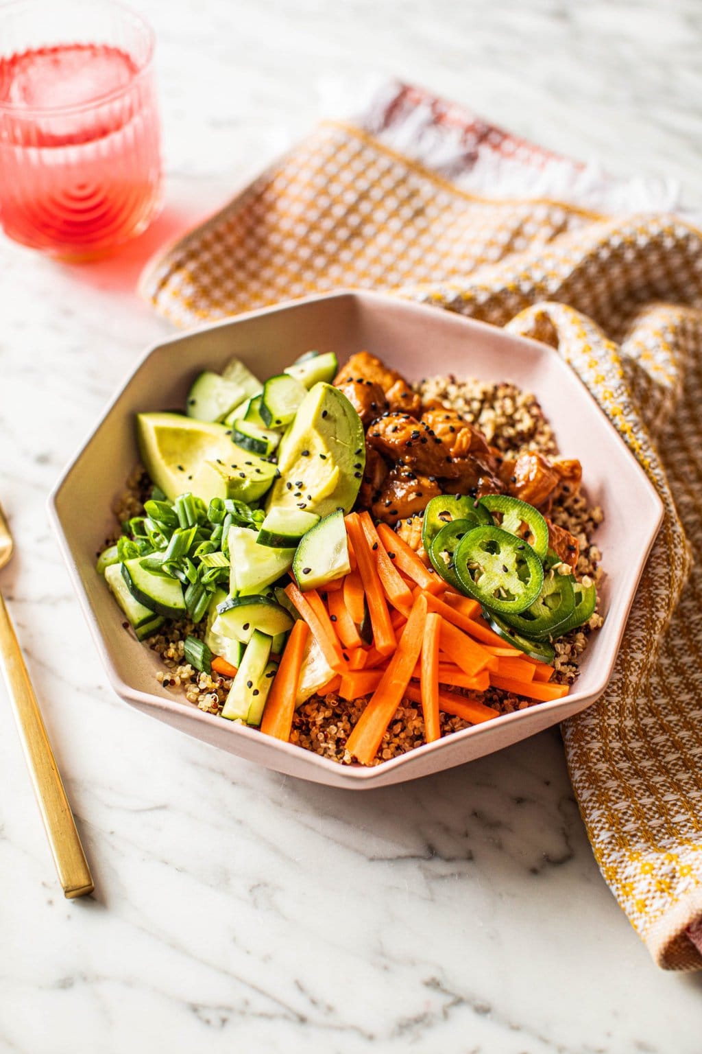 salmon and quinoa bowl topped with cucumber, carrots, avocado, jalapenos