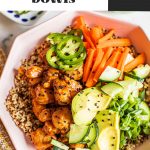 quinoa and salmon in bowl topped with cucumber, carrots, avocado, jalapenos