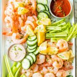 shrimp platter with celery, cucumbers, lemon wedges, cajun aioli and cocktail sauce