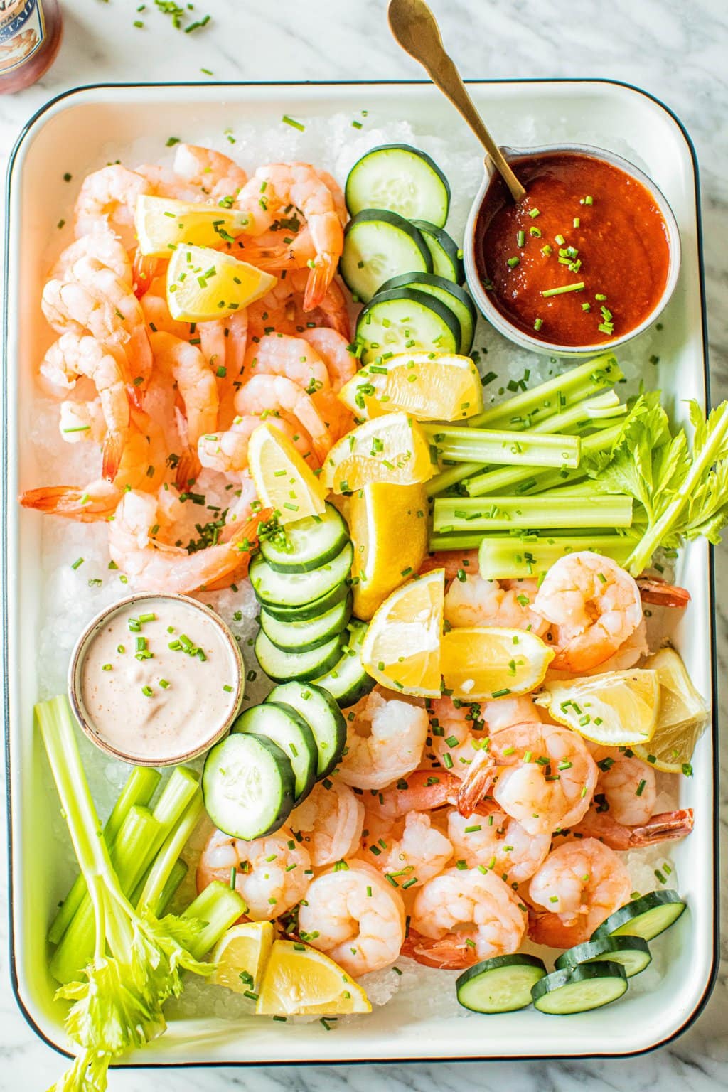 shrimp platter with celery, cucumbers, lemon wedges, cajun aioli and cocktail sauce