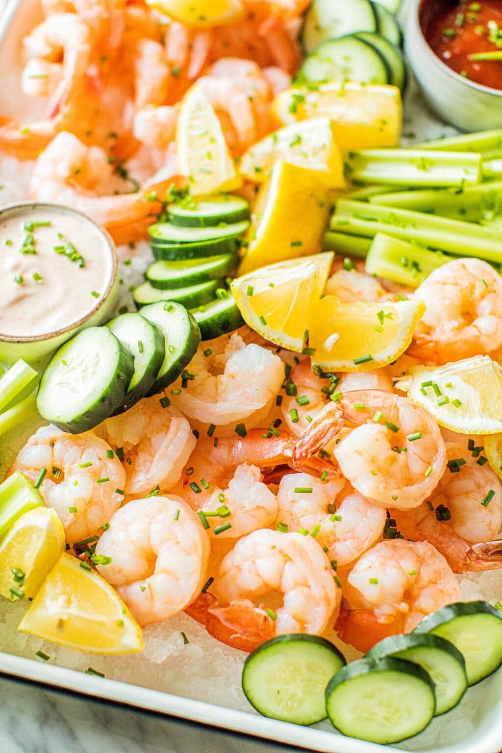 shrimp cocktail platter with celery, cucumbers, lemons, cajun aioli and cocktail sauce