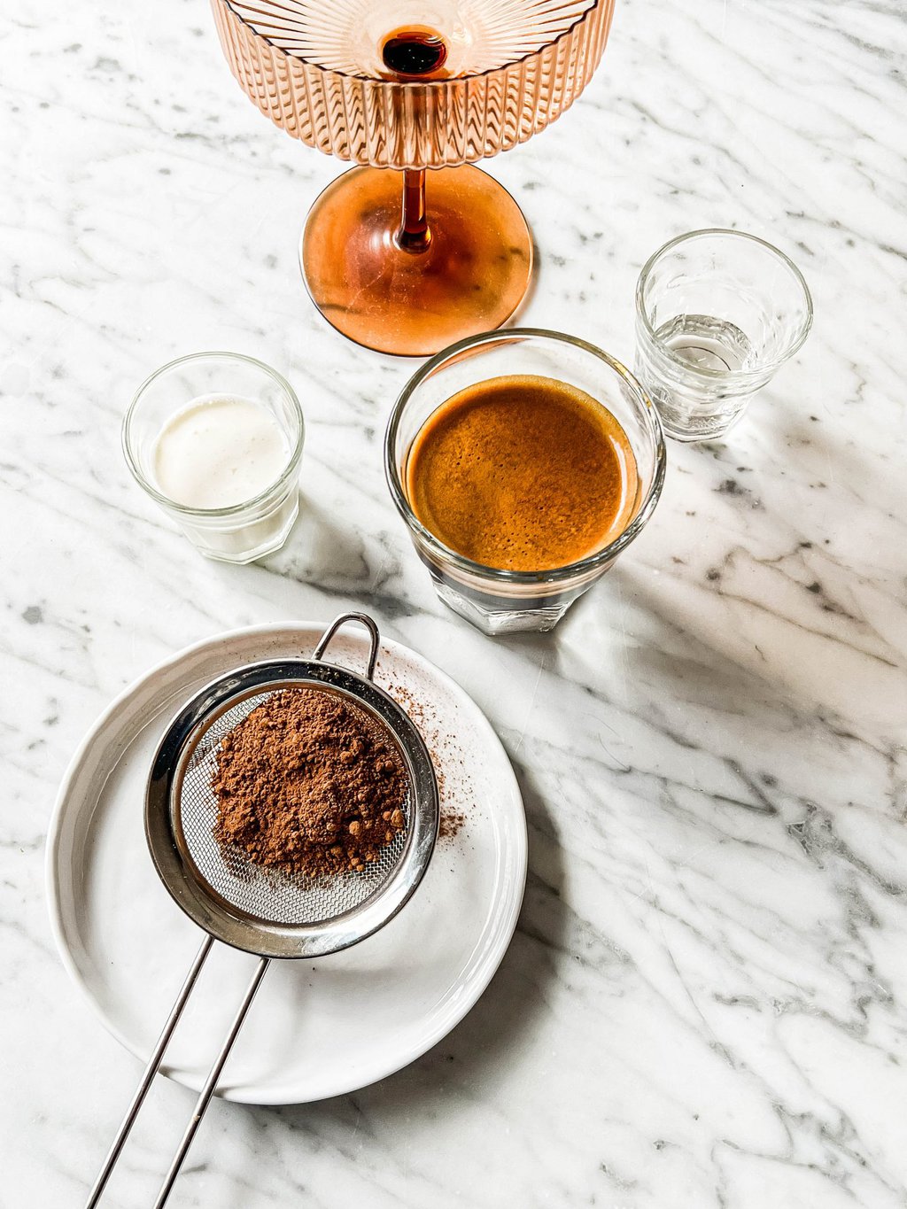 brown coupe glass, heavy whipping cream, espresso, simple syrup, cocoa powder and a sifter 