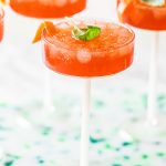 negroni spritz cocktail in couple glasses garnished with basil leaf