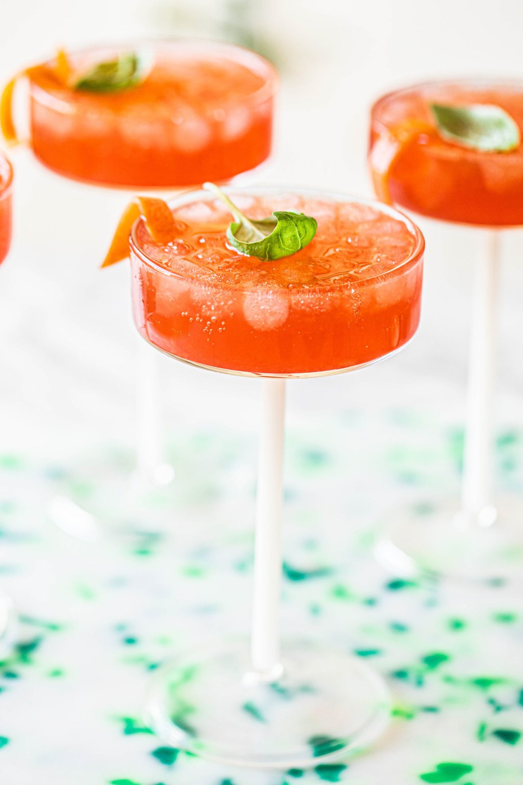 negroni spritz cocktail in couple glasses garnished with basil leaf