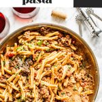 spicy sausage pasta in skillet with wooden spoon