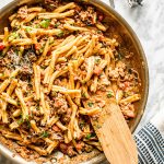 pasta with hot sausage in skillet with wooden spoon