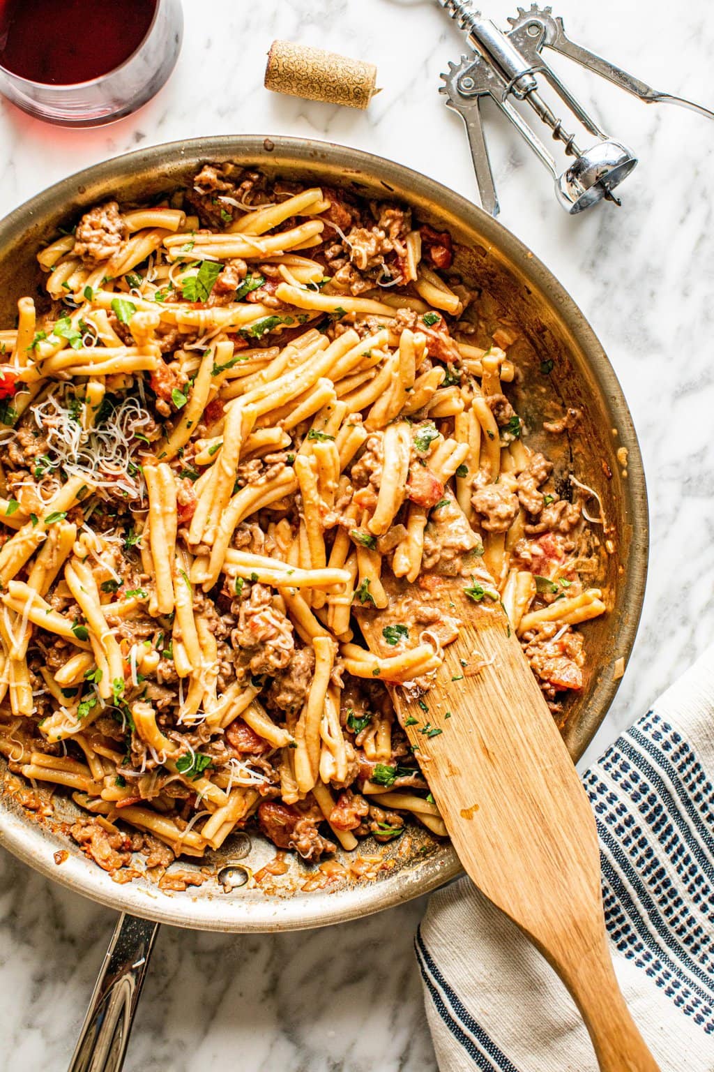 pasta with hot sausage in skillet with wooden spoon