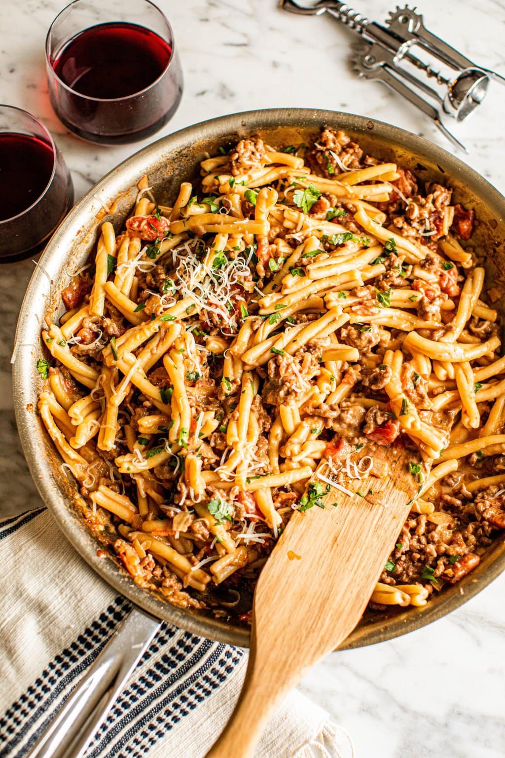 spicy sausage pasta in skillet with wooden spoon