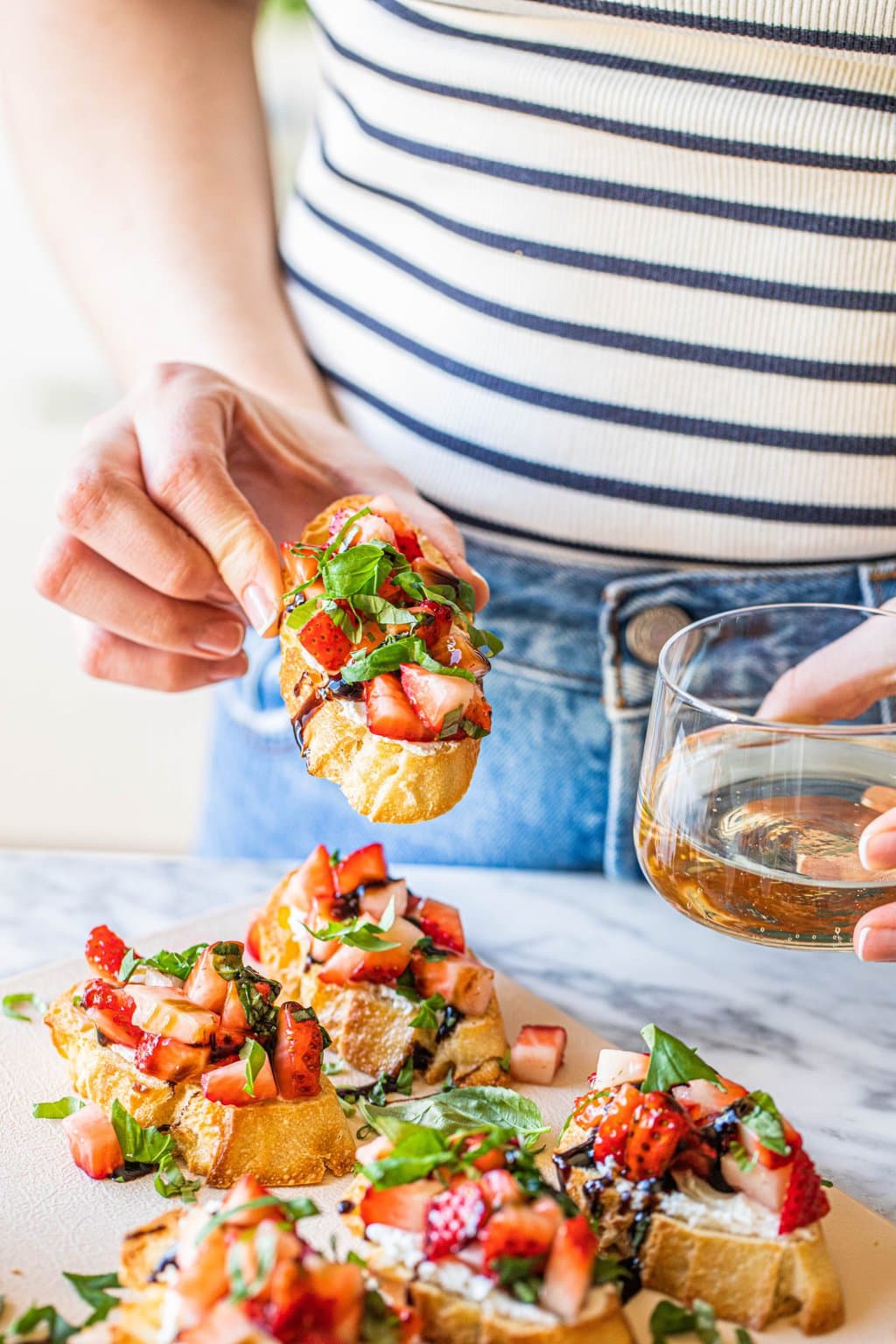 woman holding a piece of strawberry goat cheese bruschetta