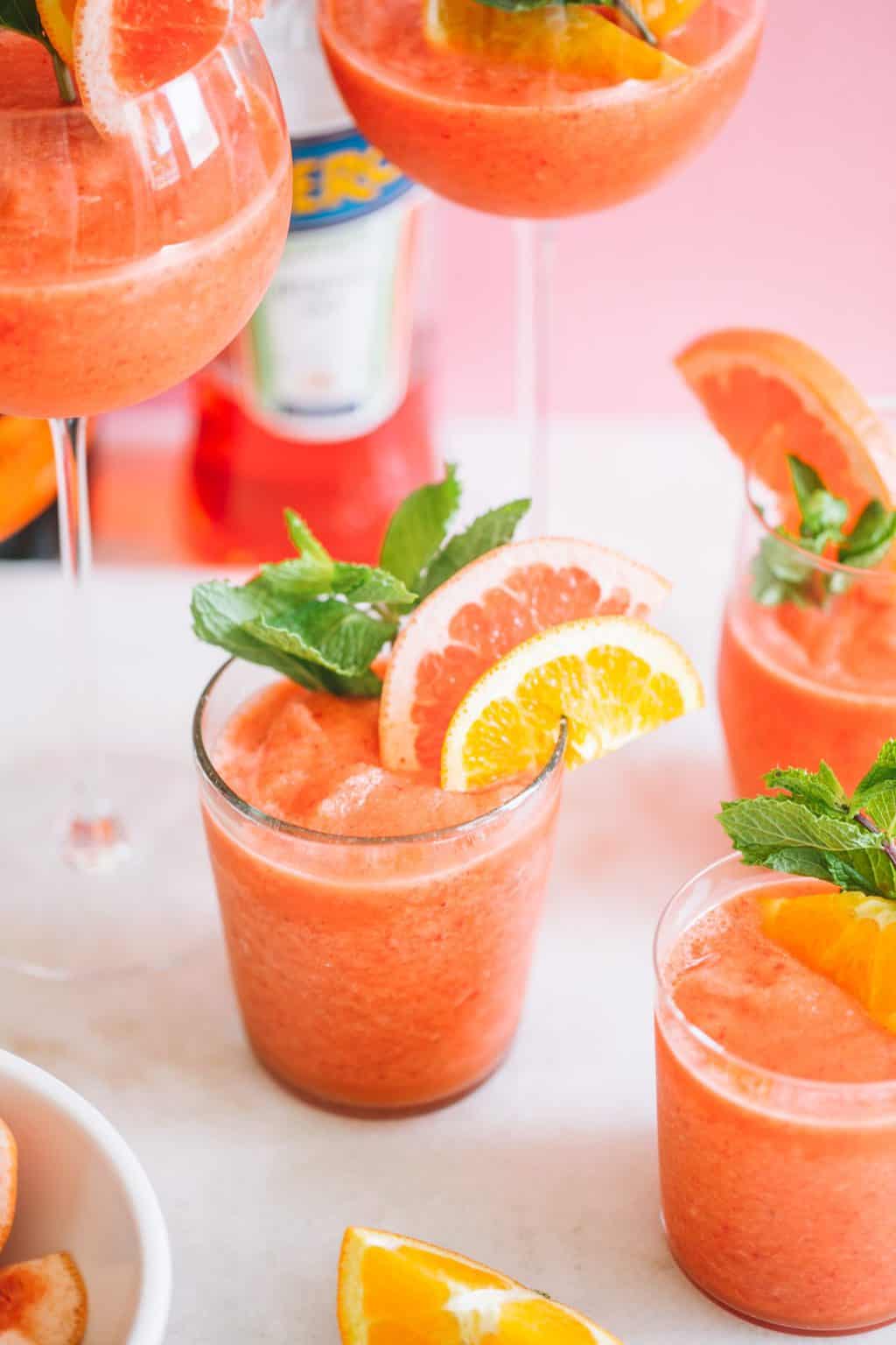 This Frozen Aperol Spritz Cocktail, with a vibrant sunset-orange hue, is filled with Aperol, orange juice, strawberries and Prosecco, then blended up into a frozen frothy cocktail. It’s a refreshing summer cocktail recipe that’s easy to prep ahead and will make you feel like your backyard is an Italian courtyard.