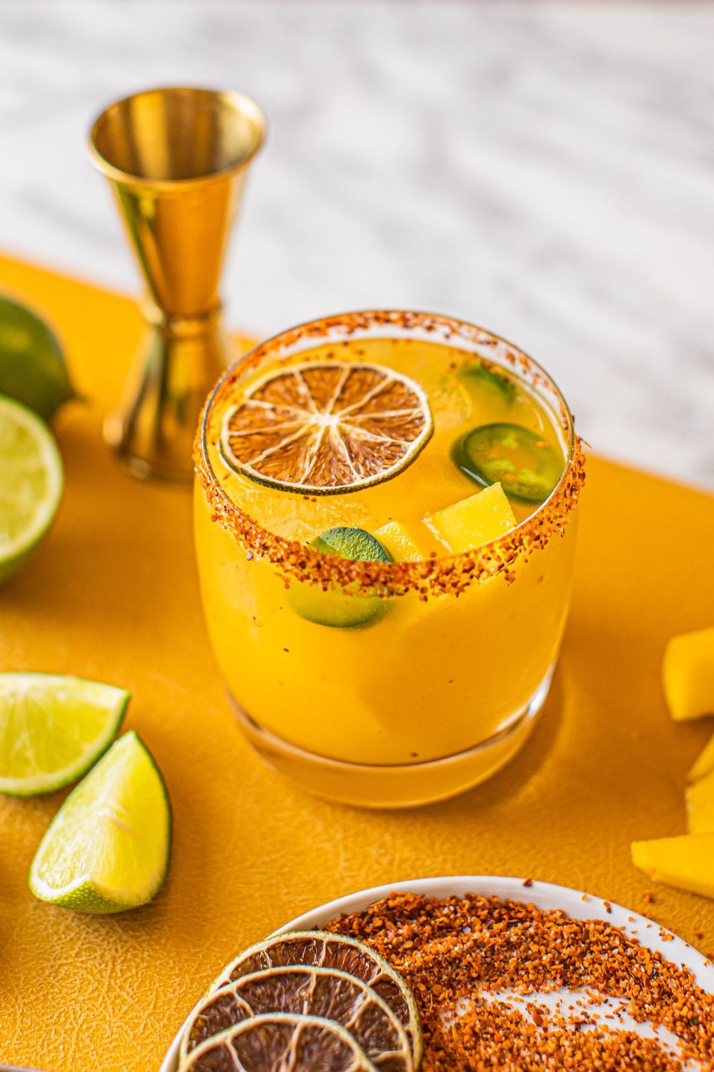 woman's hand grabbing spicy jalapeno mango margarita in low ball glass